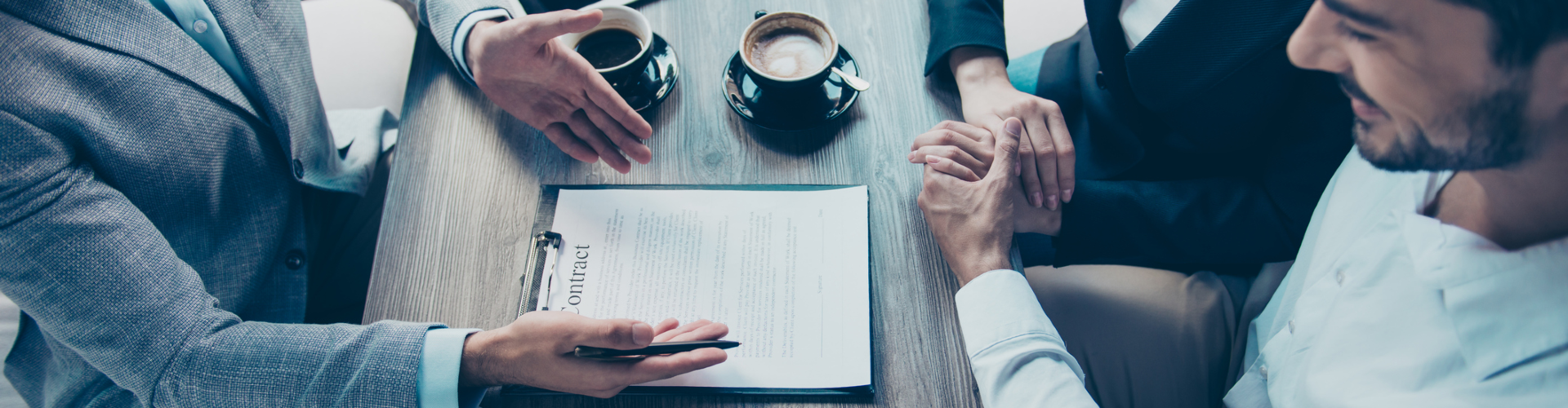 A group of people sitting at a table looking at a paper.
