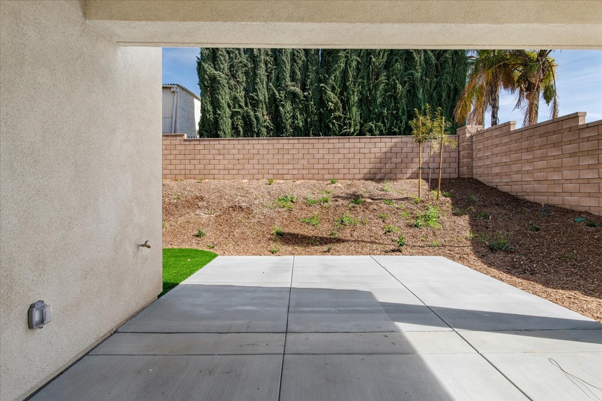 A concrete patio with a brick wall and trees.