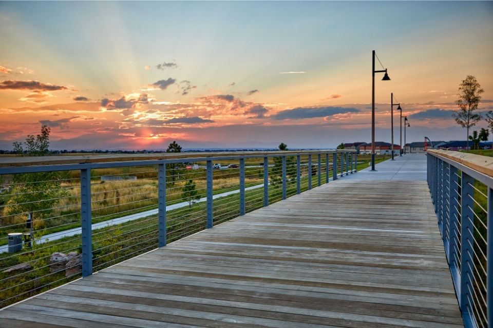 A wooden walkway with blue railings and a sunset.