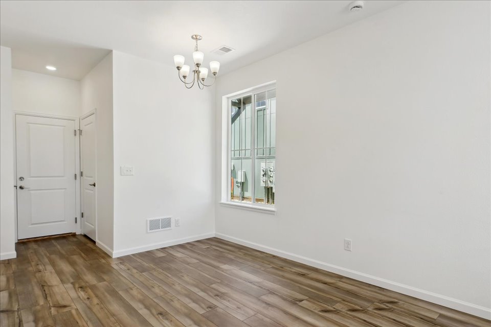 A room with a wood floor and a window with a light on.