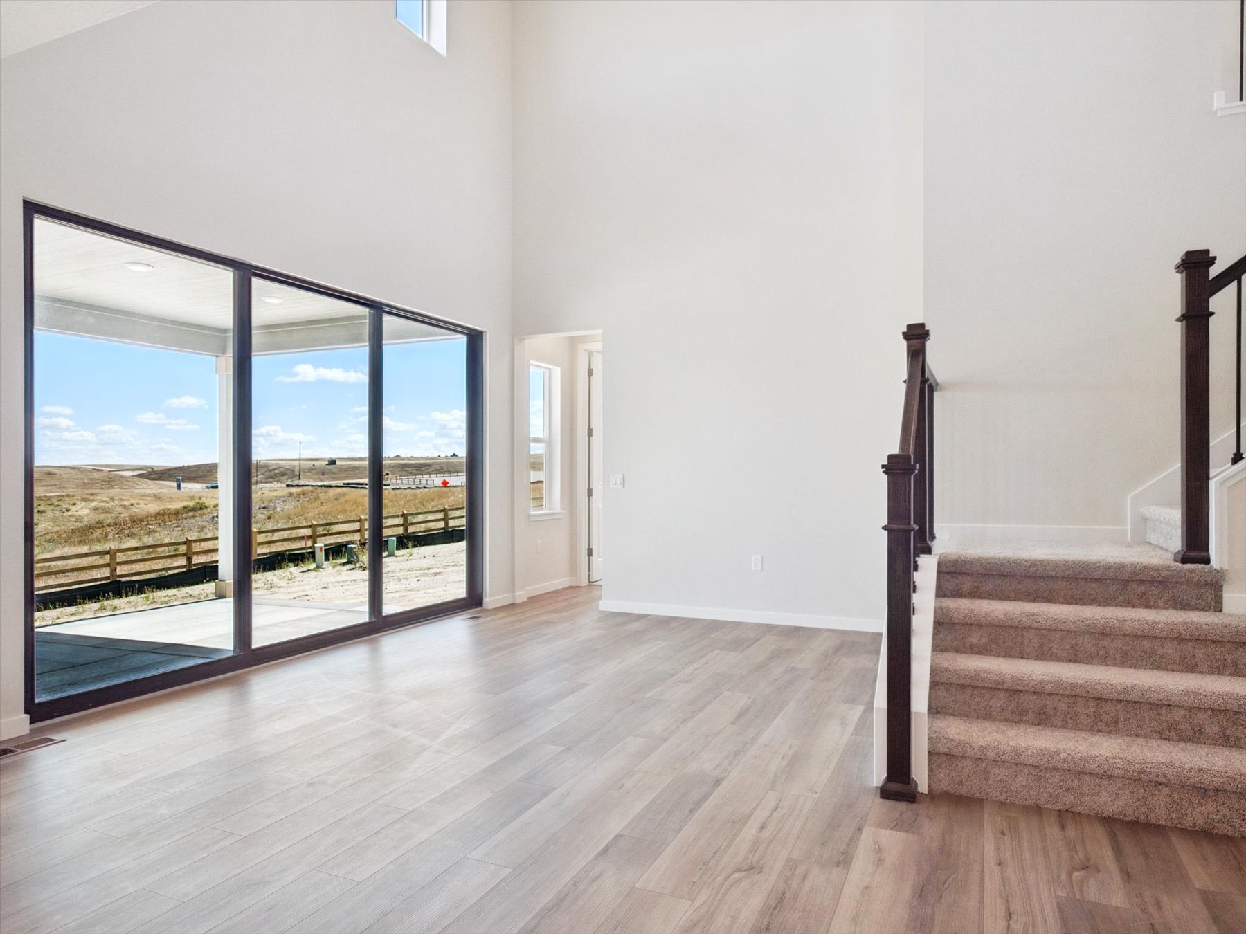 A room with a wood floor and a wood staircase with a view of the ocean.