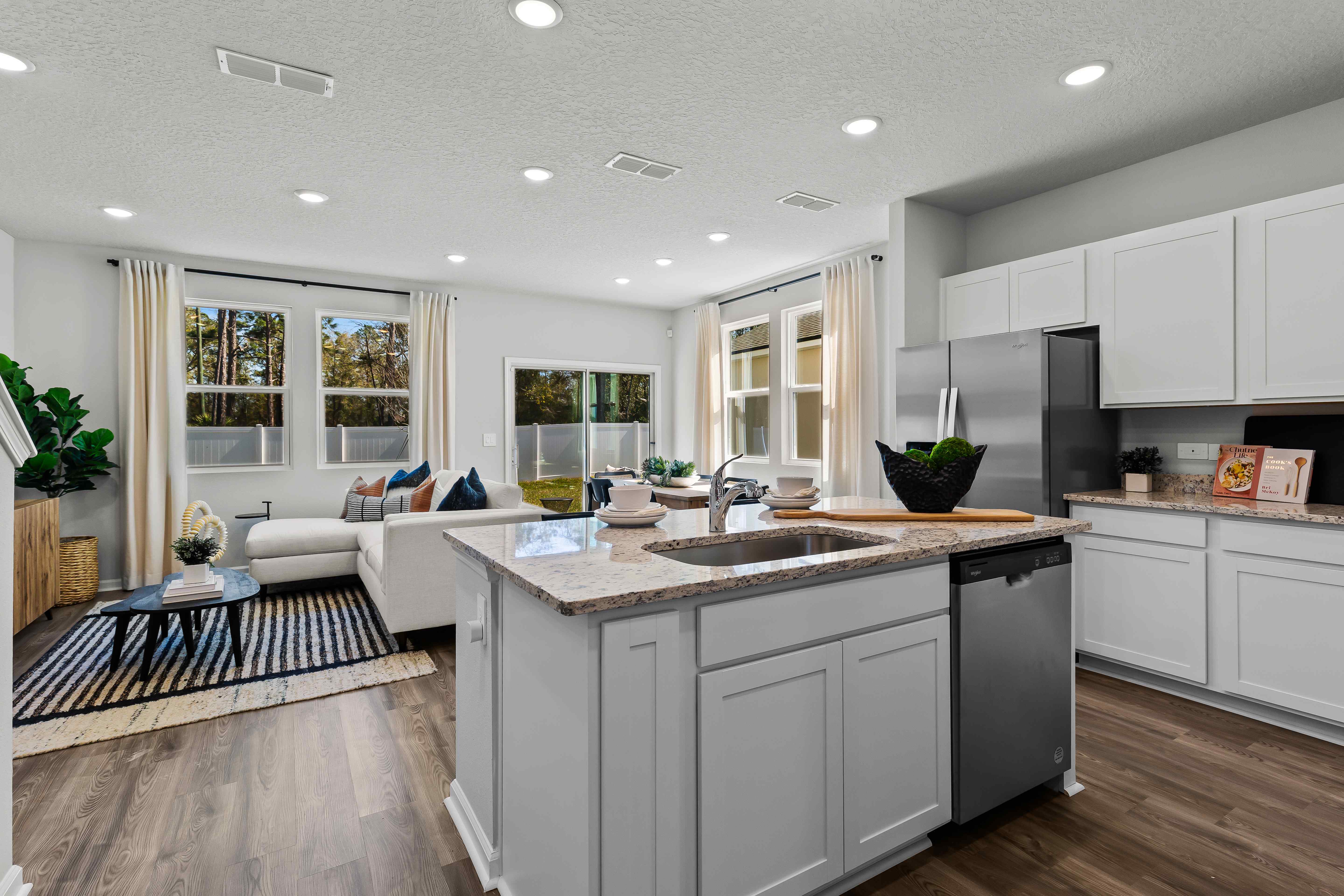 Davor Model Paired Home White Kitchen Island overlooking living room at The Landings at Pecan Park