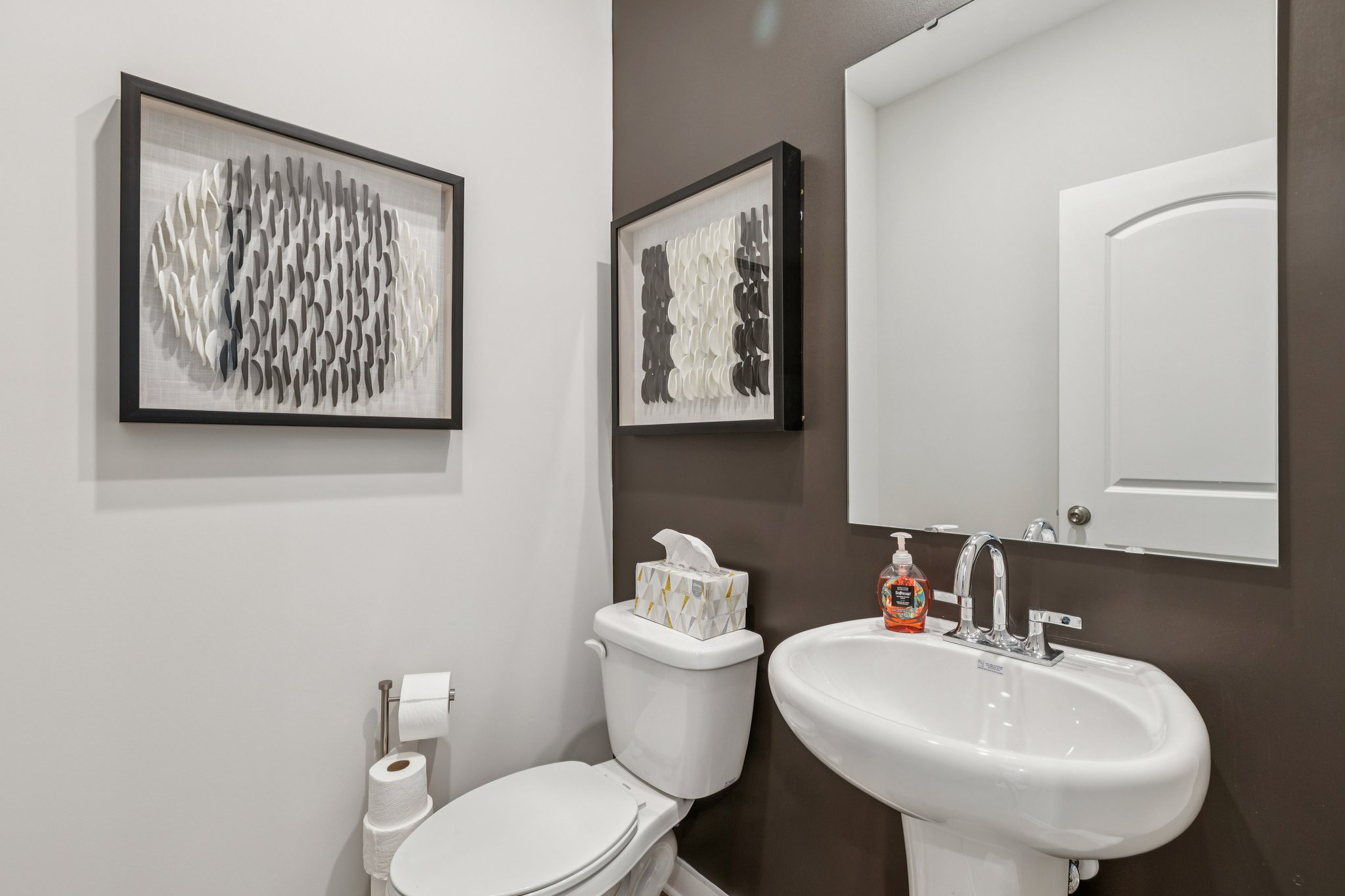 A bathroom with a sink toilet and a mirror.