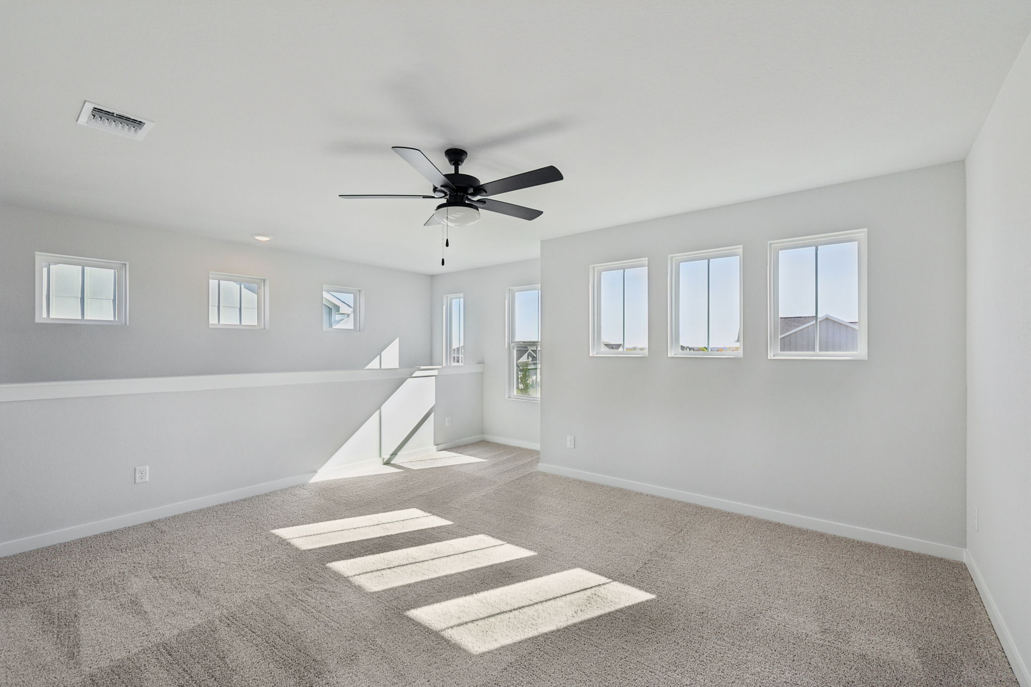 A room with a ceiling fan and a carpet.