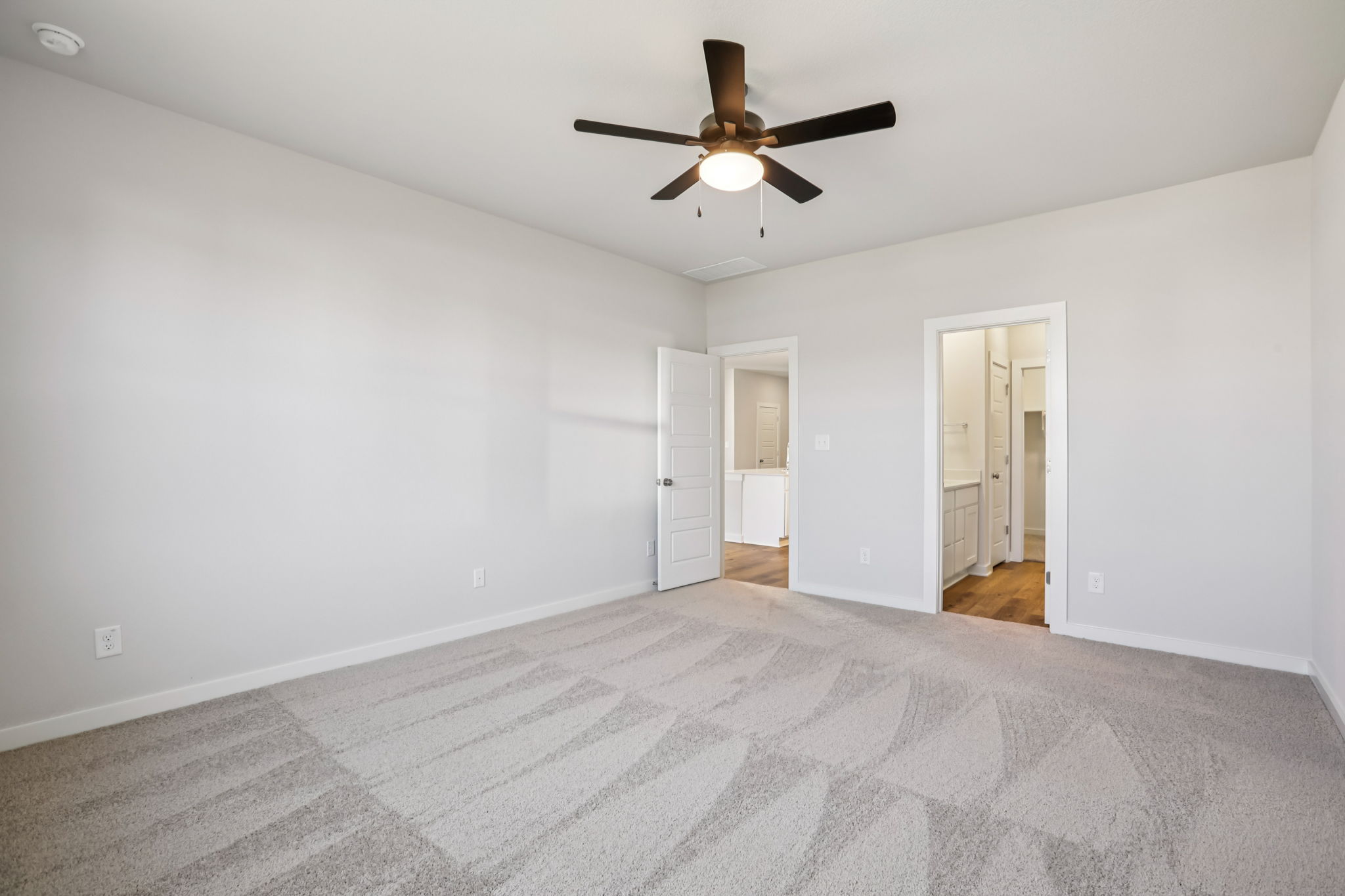 A room with a ceiling fan and a carpet.