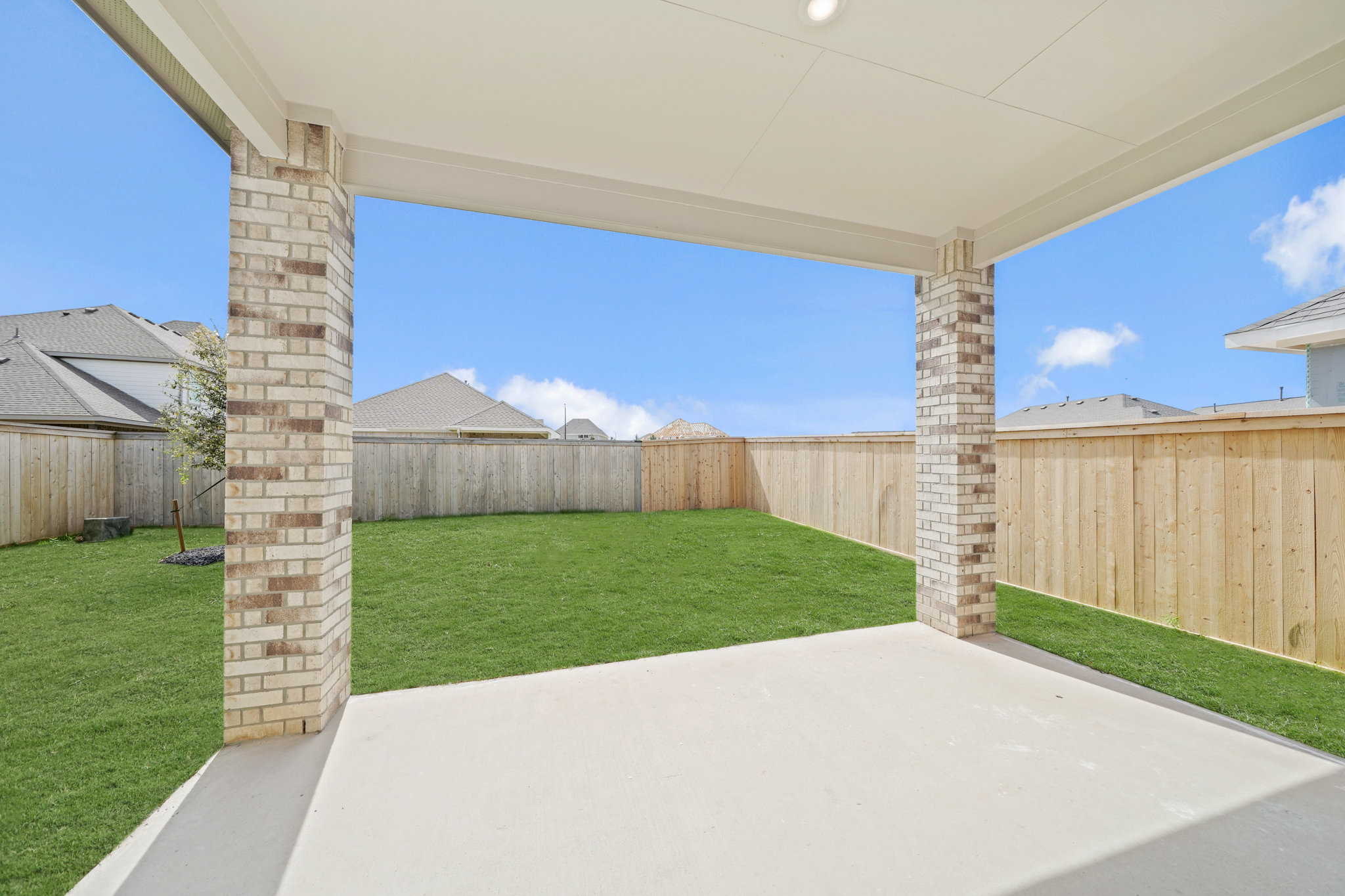 A fenced in yard with a brick wall and a stone structure.
