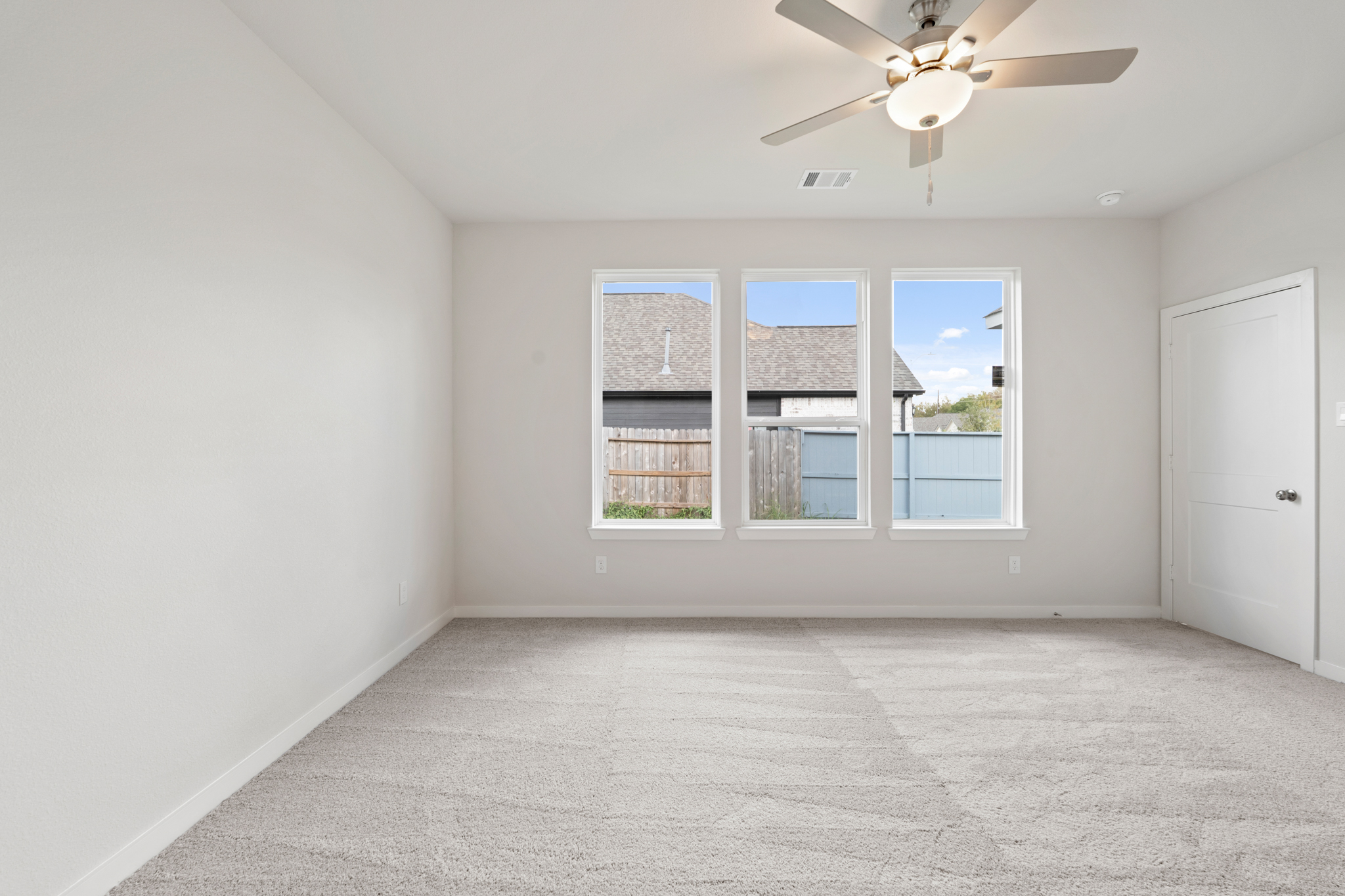 A room with a ceiling fan and a window with a view of the ocean.
