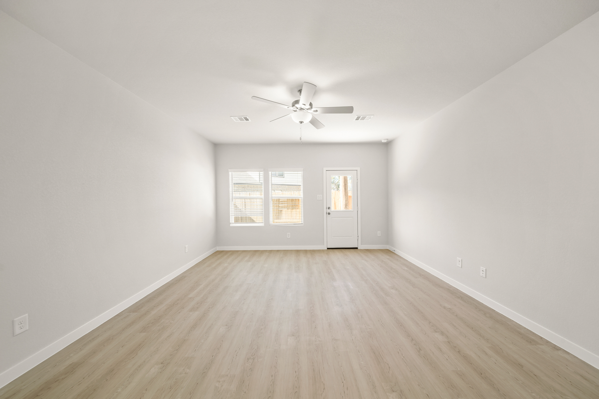 A room with a ceiling fan and a wood floor.