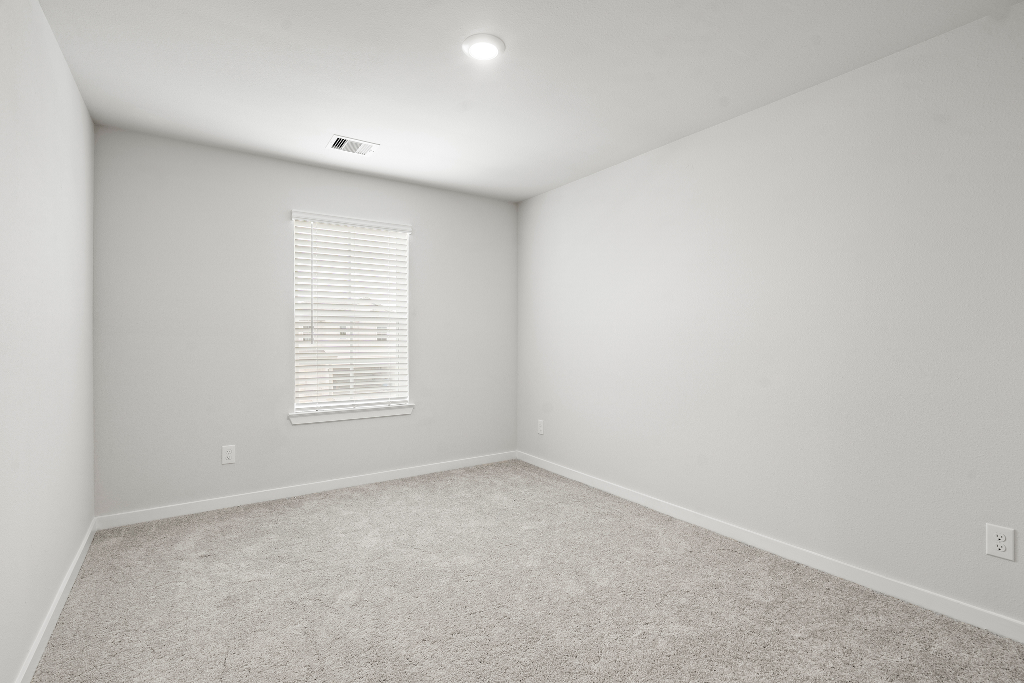A room with a white wall and a light on the ceiling.