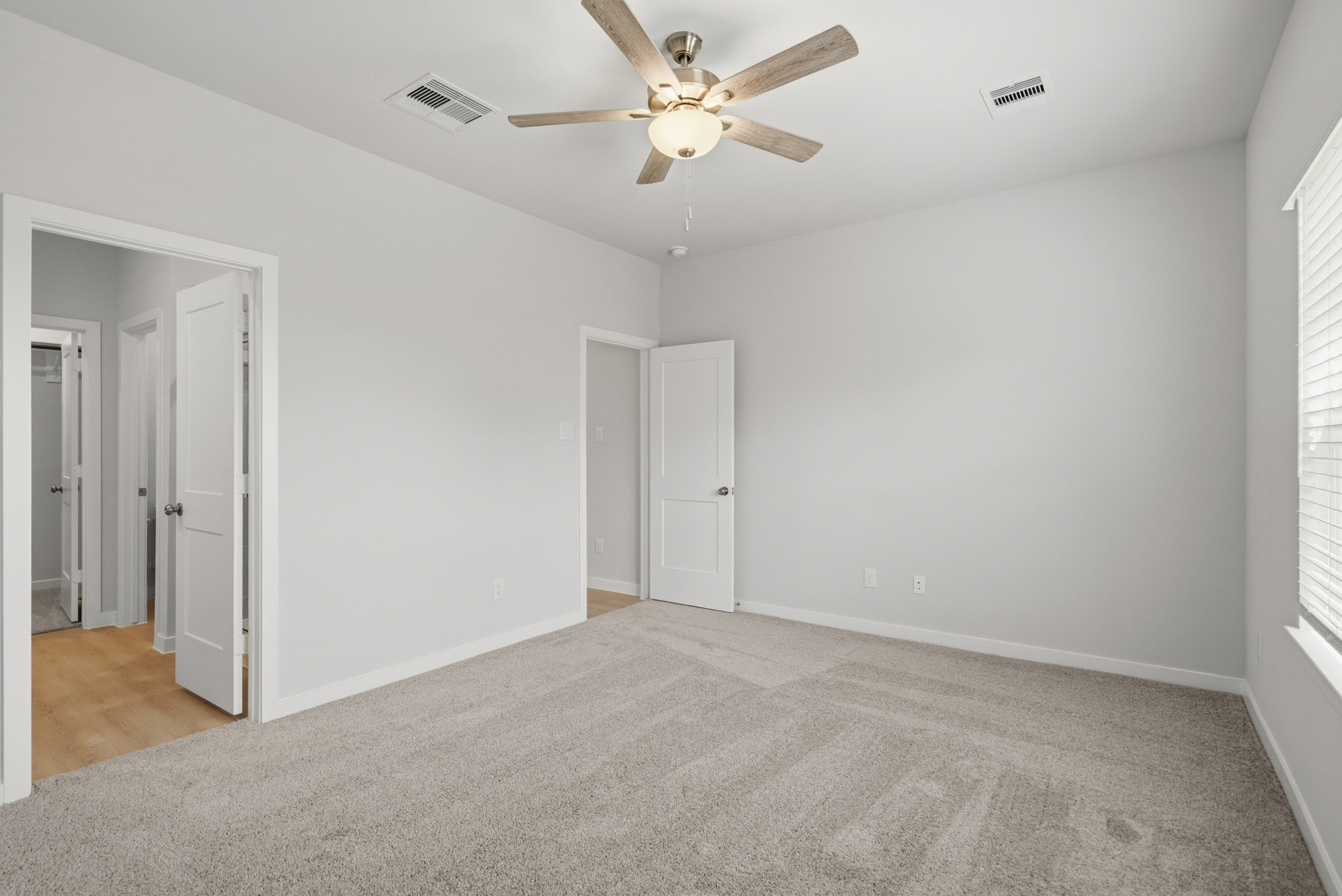 A room with a ceiling fan and white doors.