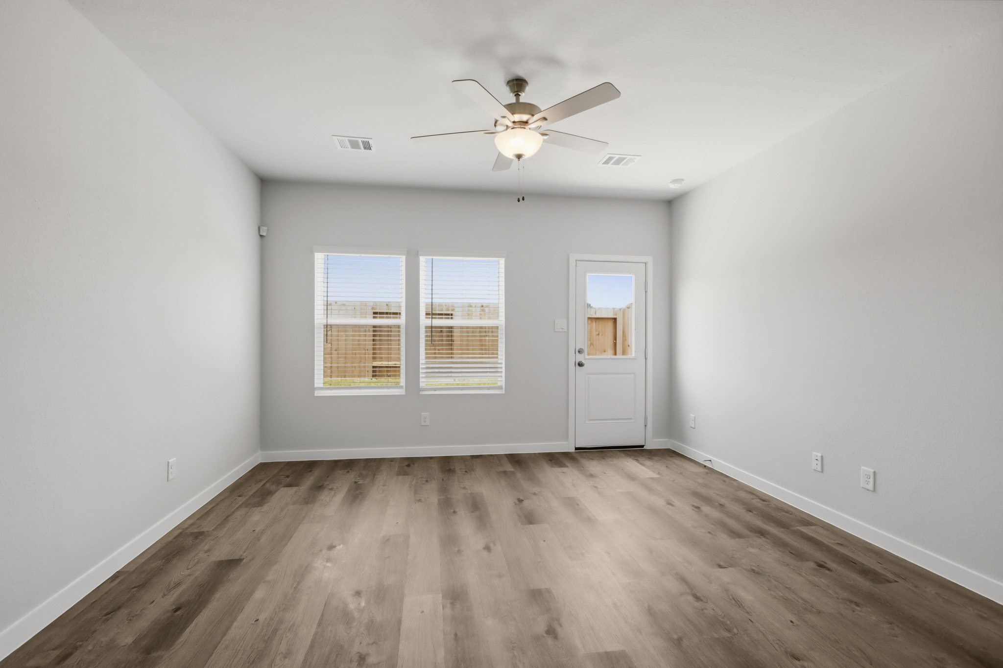 A room with a ceiling fan and a wood floor.