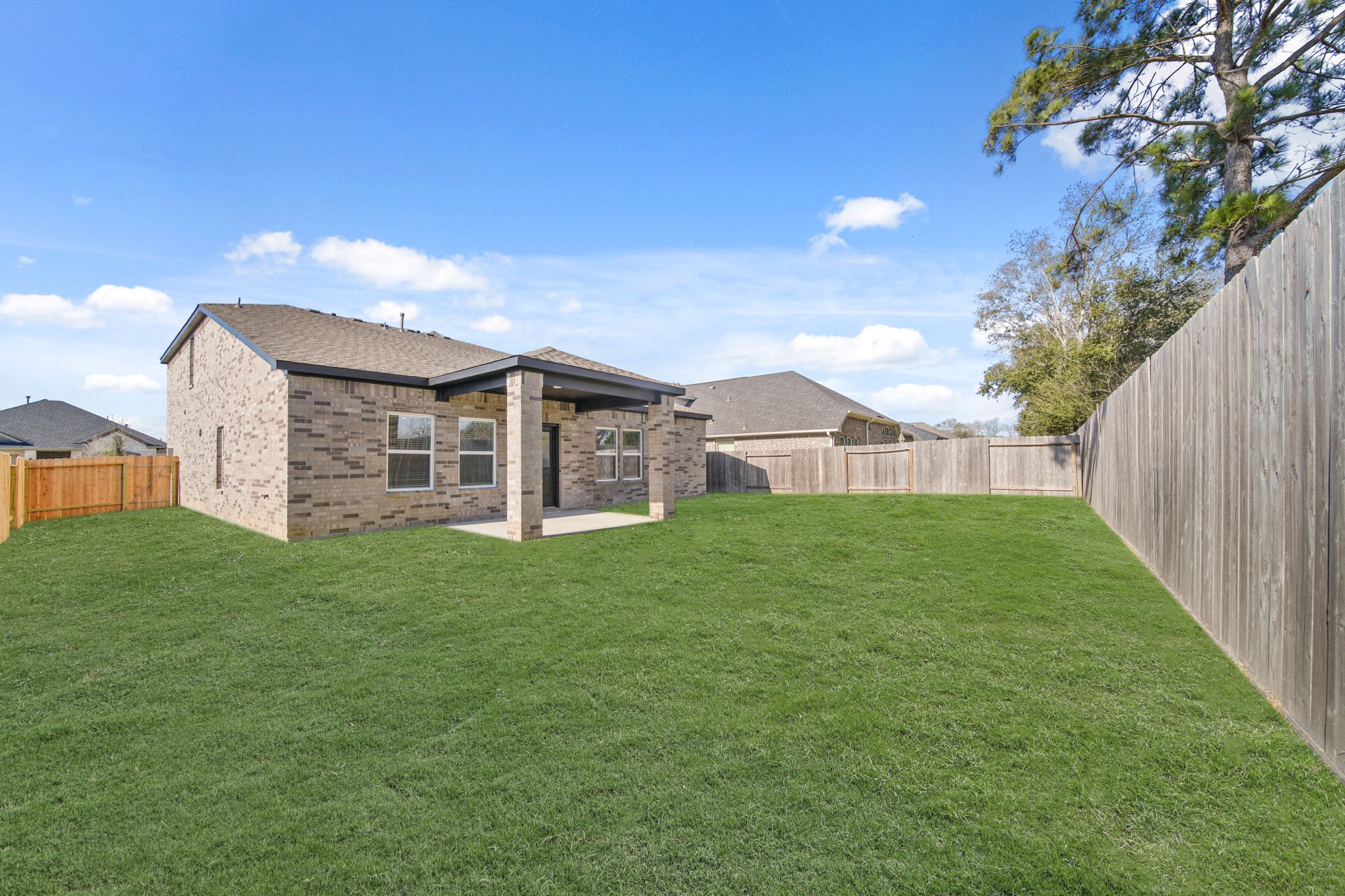 A large green lawn with a fence and a house in the background.
