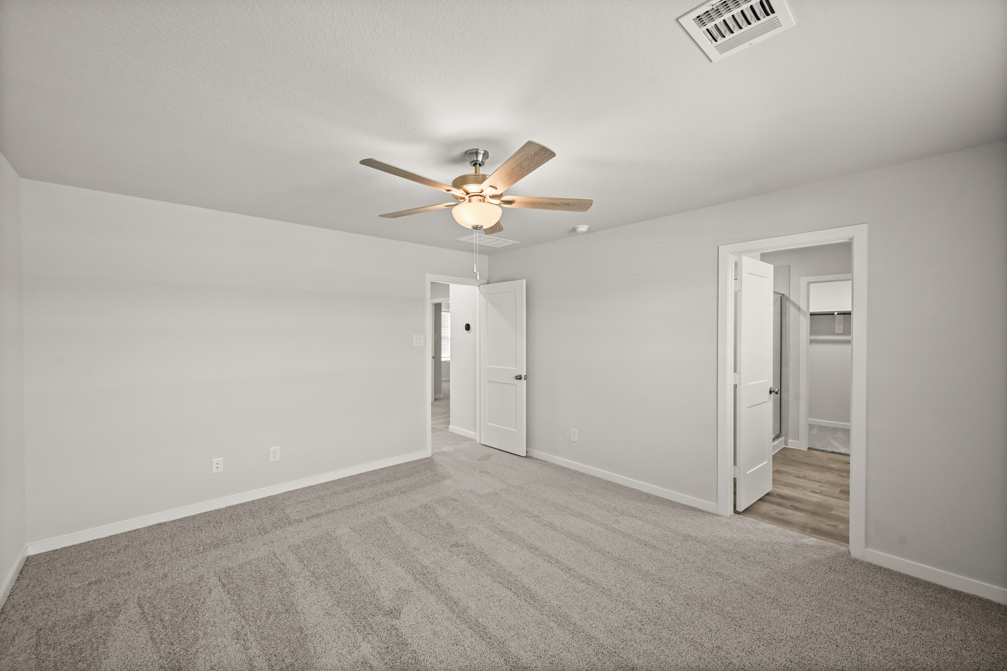 A room with a ceiling fan and a door.