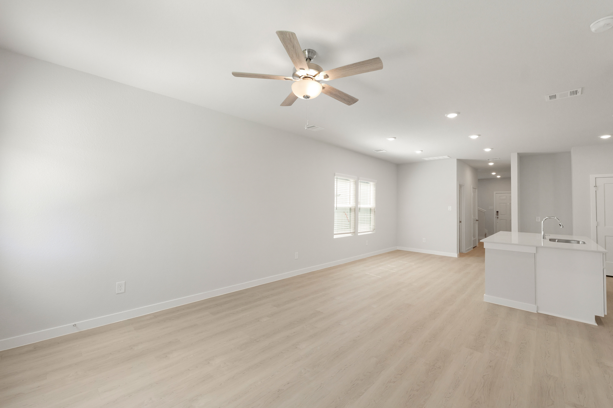 A large empty room with a ceiling fan and a wood floor.