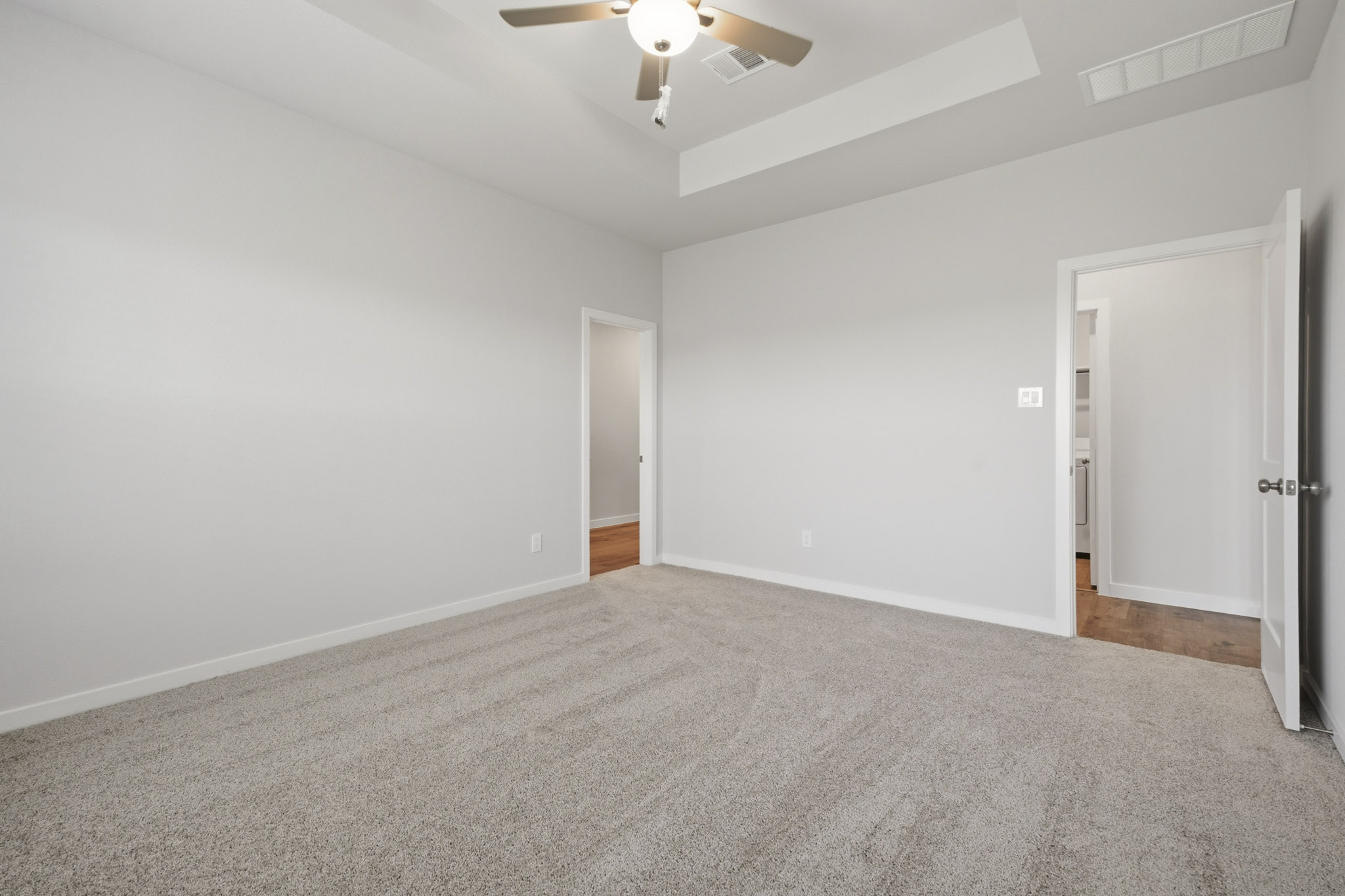 A room with a ceiling fan and a carpet.