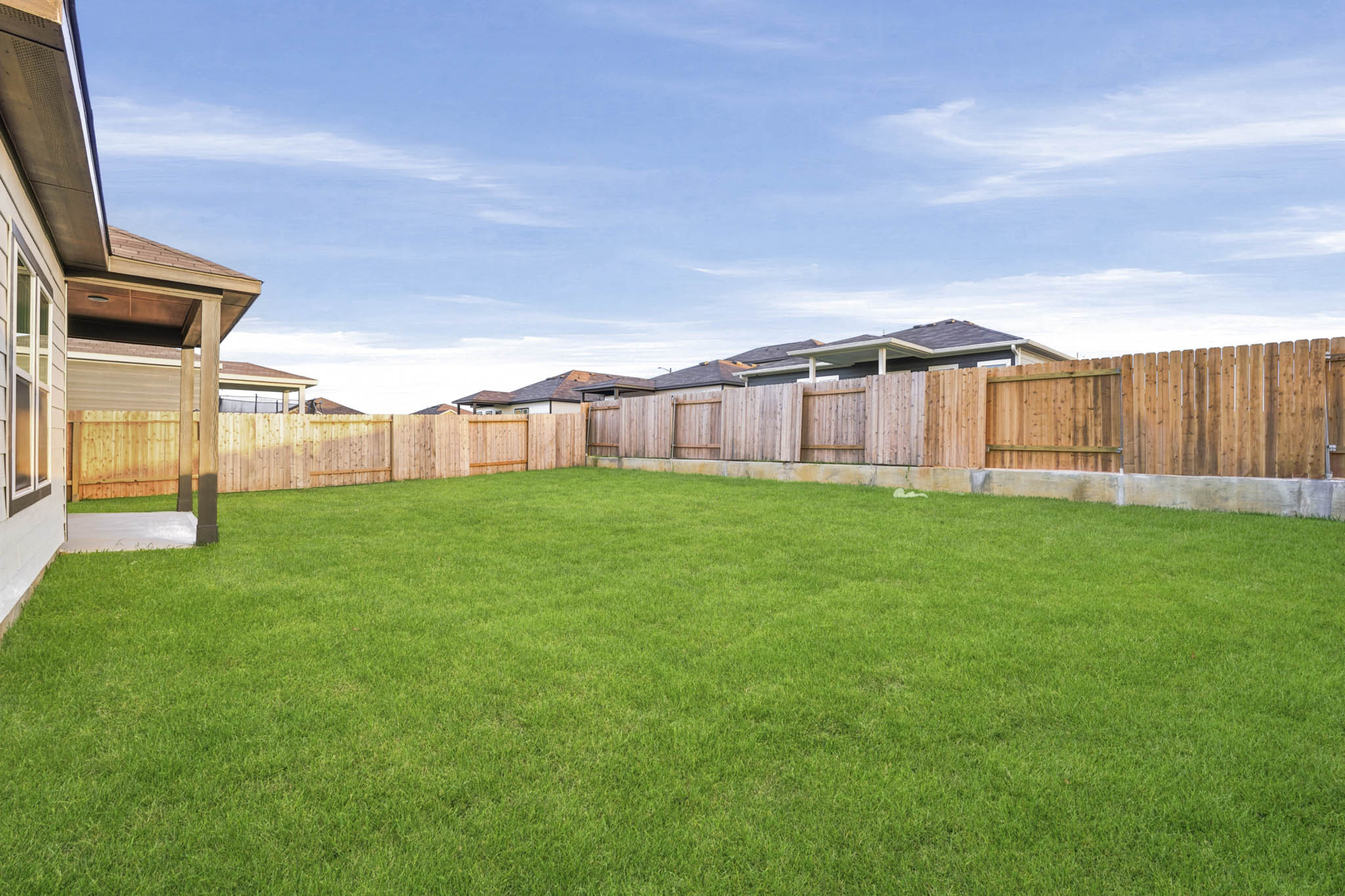 A fenced in yard with a house in the background.