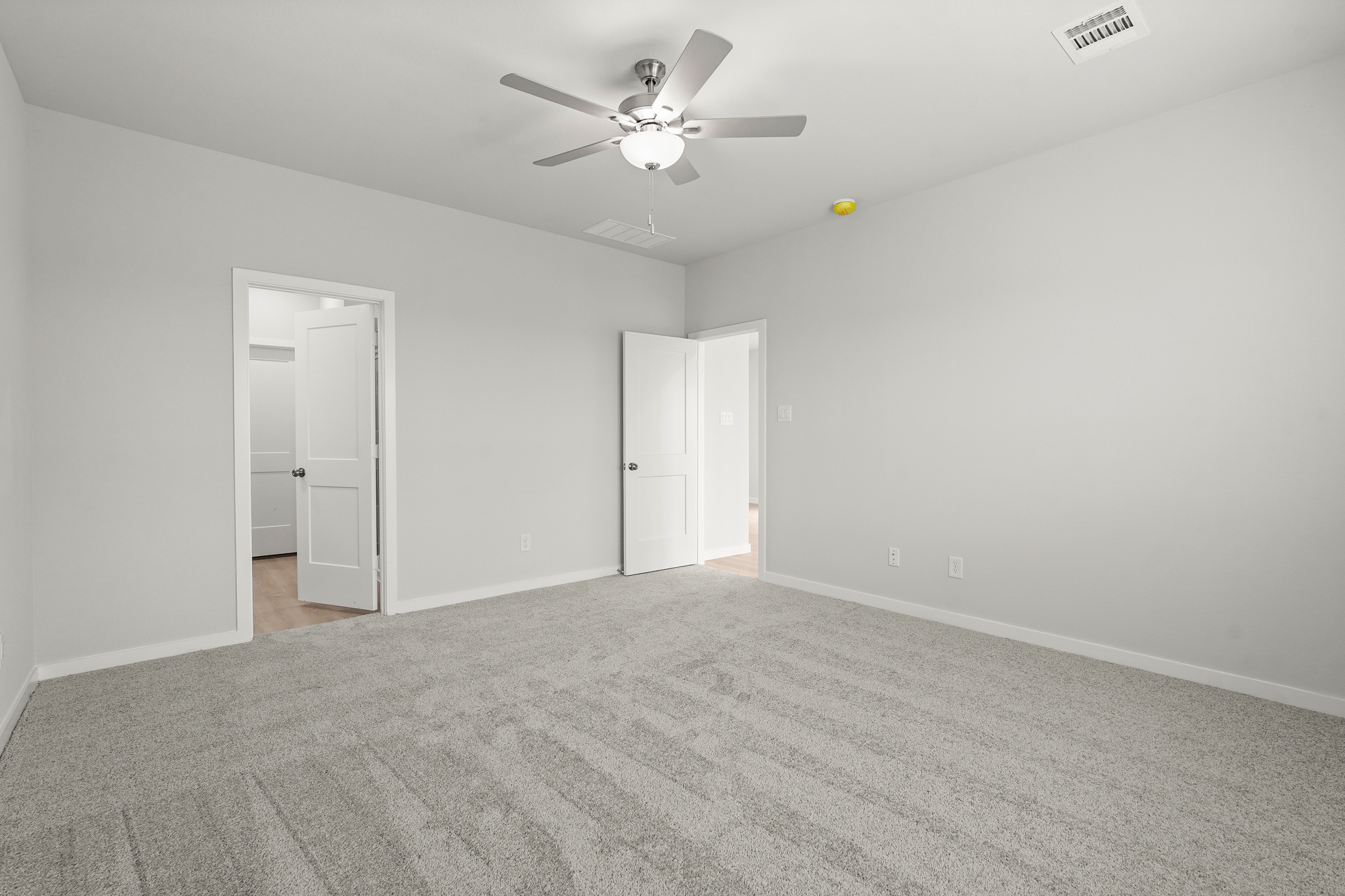 A room with a ceiling fan and a door.