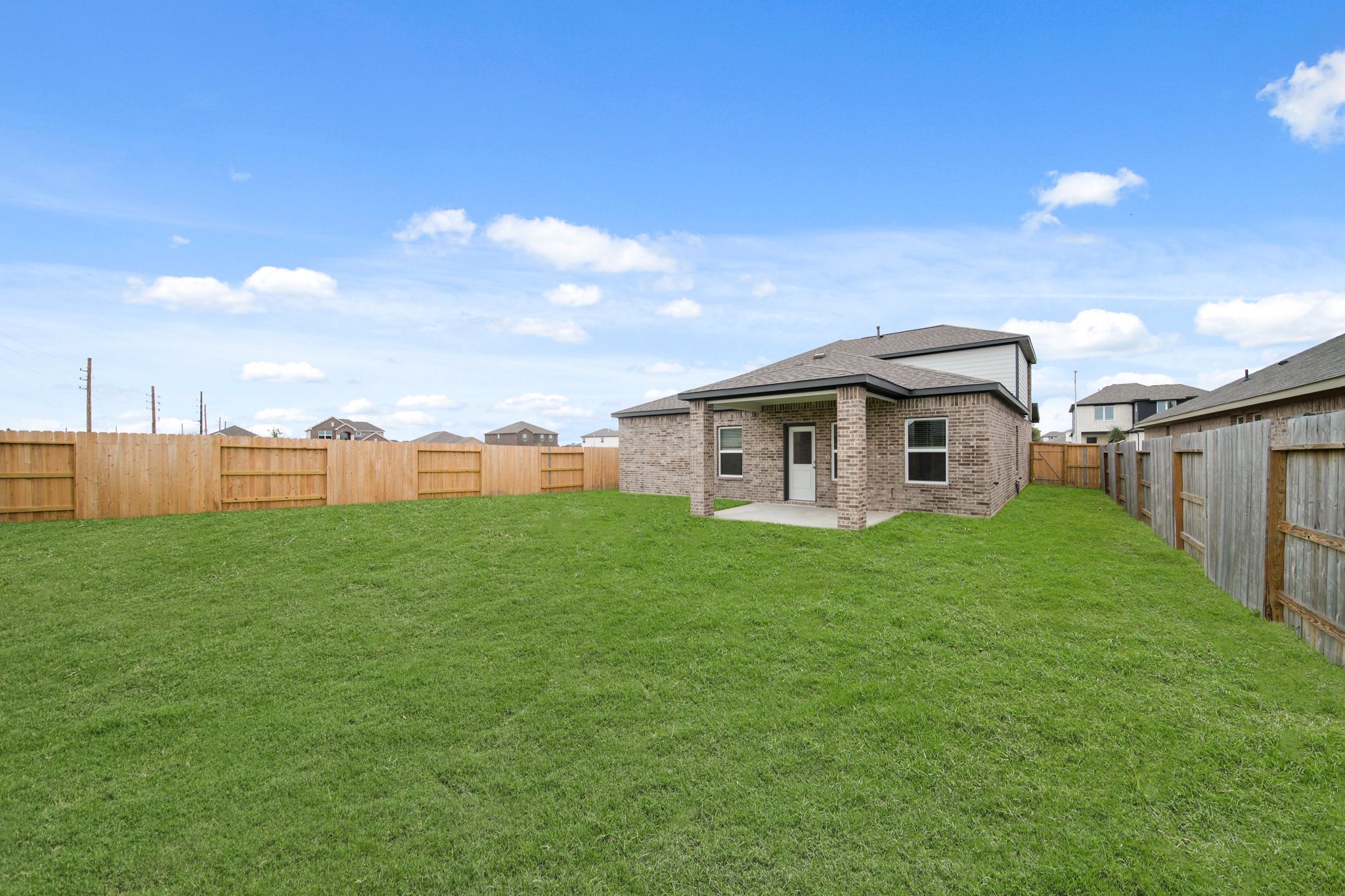 A grassy yard with a fence and a house in the background.