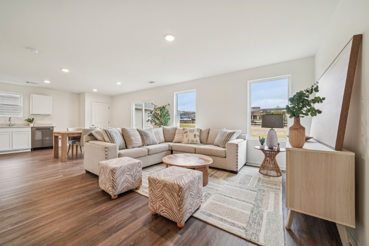 A living room with a large white wall and a wood floor.
